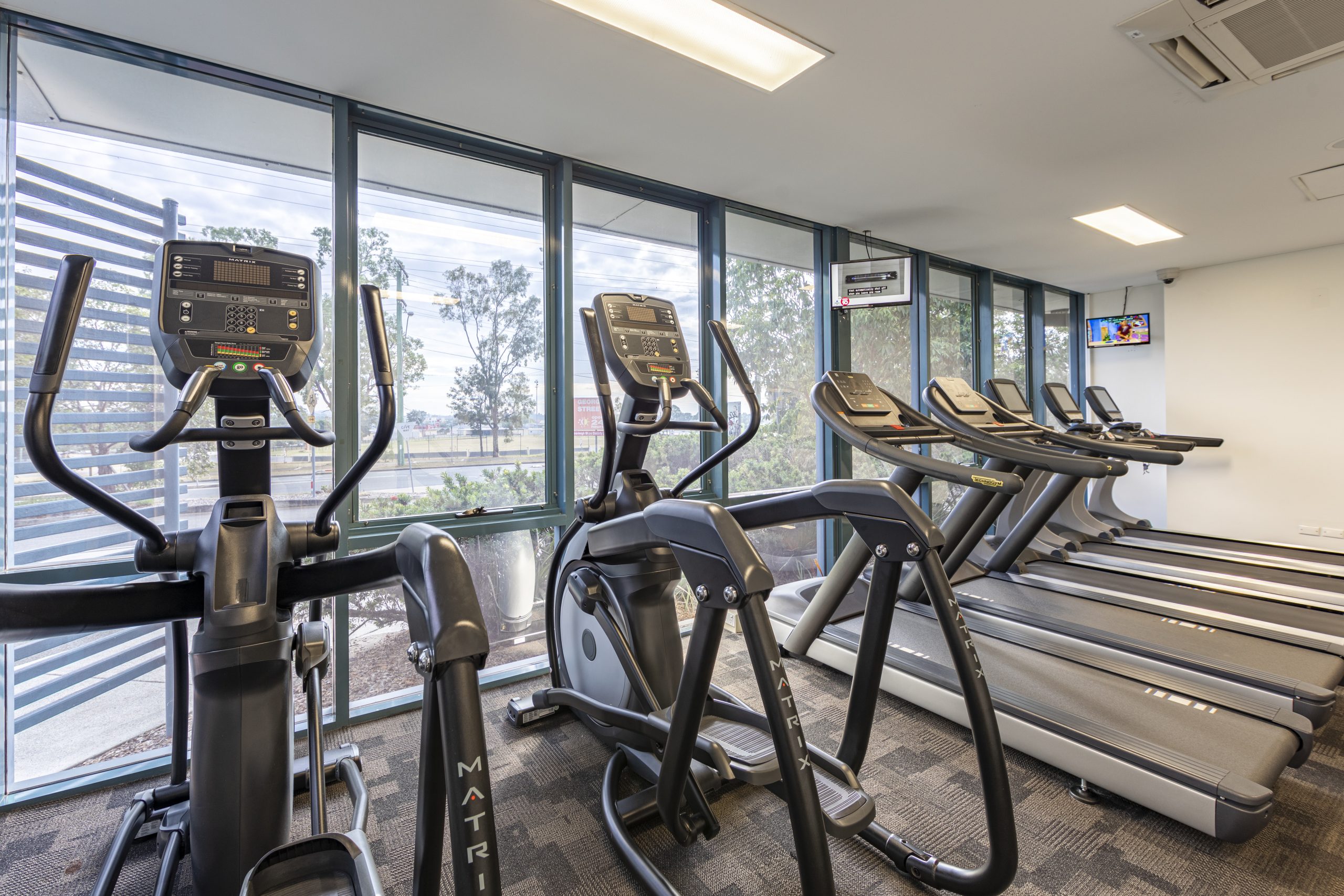 Treadmills lined up against windows in the cardio room at Mount Warren Fitness Centre